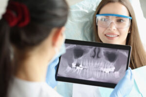 a smiling patient with a dentist who is reviewing a dental X-ray